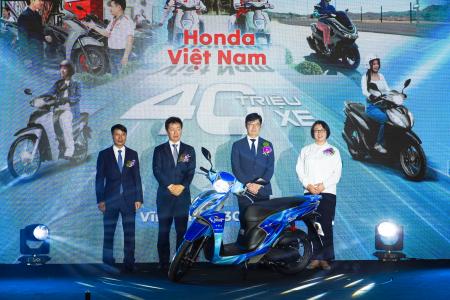 　生産４千万台目の記念のバイクとホンダの塚本飛佳留開発生産統括部長（左から２人目）ら＝３０日、ハノイ郊外（共同）