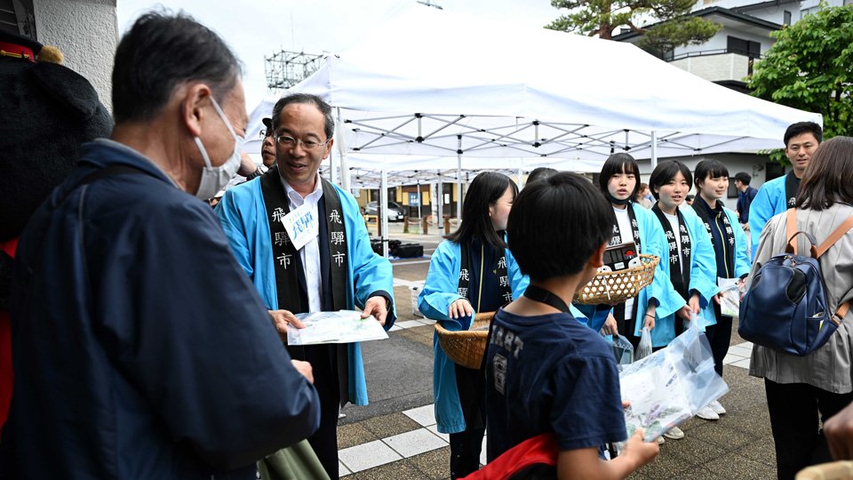 観光客らを出迎える都竹淳也市長（左から２人目）や中学生ら＝飛騨市古川町金森町、ＪＲ飛騨古川駅