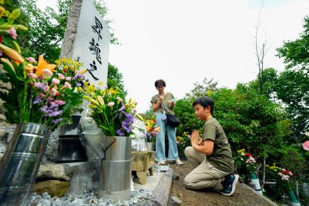 　日航機墜落事故現場の尾根に立つ「昇魂之碑」で手を合わせる遺族＝１２日午前、群馬県上野村
