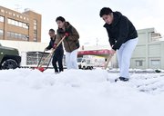 雪の舞う中、朝から駐車場の雪かきに追われる人たち＝２３日午前８時１７分、岐阜市島栄町