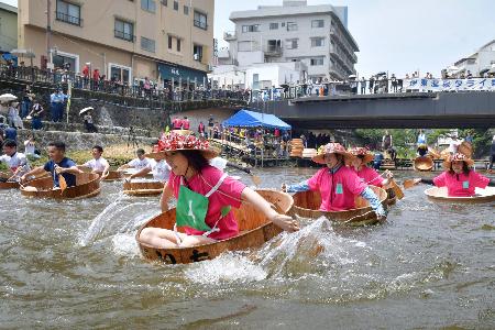 　「松川タライ乗り競走」で、水しぶきを上げながら川を下る出場者＝６日午前、静岡県伊東市