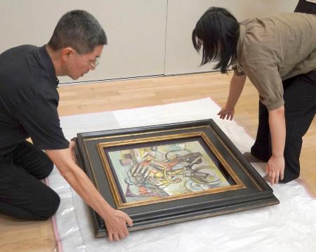 　贋作と判断した油彩画「自転車乗り」を梱包する徳島県立近代美術館の学芸員＝１５日午後、徳島市