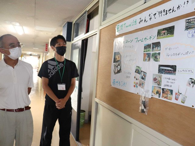 生徒が制作した「全校旅行」のポスターを眺め、成長を実感する井上博詞校長（左）＝岐阜市金宝町、草潤中学校
