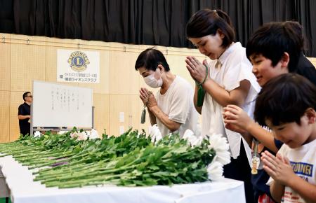 　２０１７年の九州北部の豪雨から８年となり、営まれた追悼行事で献花し手を合わせる住民ら＝６日午前、福岡県朝倉市
