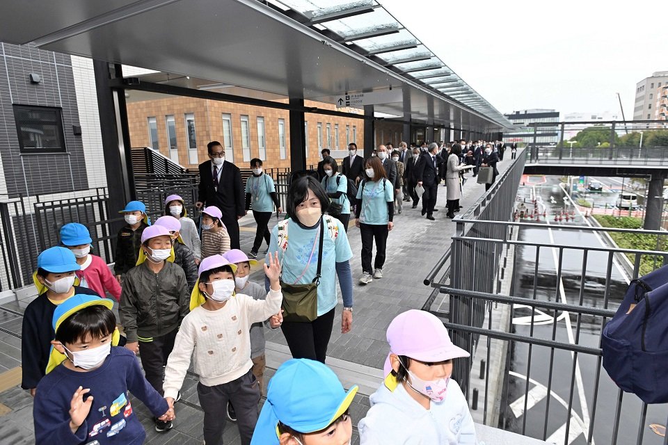 再開発地区とＪＲ多治見駅をつなぐ歩行者デッキを歩き初めする子どもたち＝多治見市本町