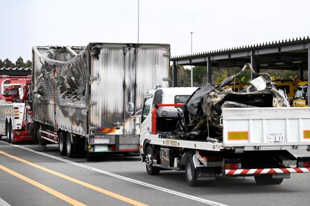 　事故があった新名神高速下り線の野登トンネルから運び出された焼けたトラックと車両（荷台上）＝２０日午後０時２３分、三重県菰野町