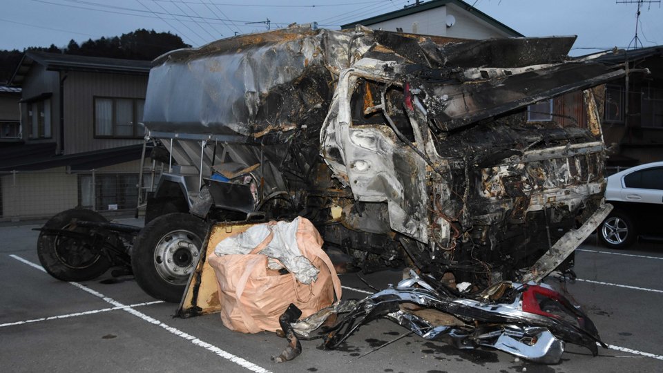 県道ののり面に横転して炎上し、車内から遺体が見つかった大型トラック＝１６日午後、高山署