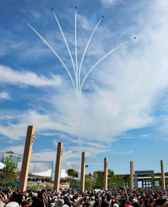　薄雲がかかった大阪・関西万博会場の上空を展示飛行する航空自衛隊のアクロバットチーム「ブルーインパルス」。大勢の来場者が妙技を見守り大きな歓声や拍手が沸いた＝１２日午後、大阪市此花区の夢洲