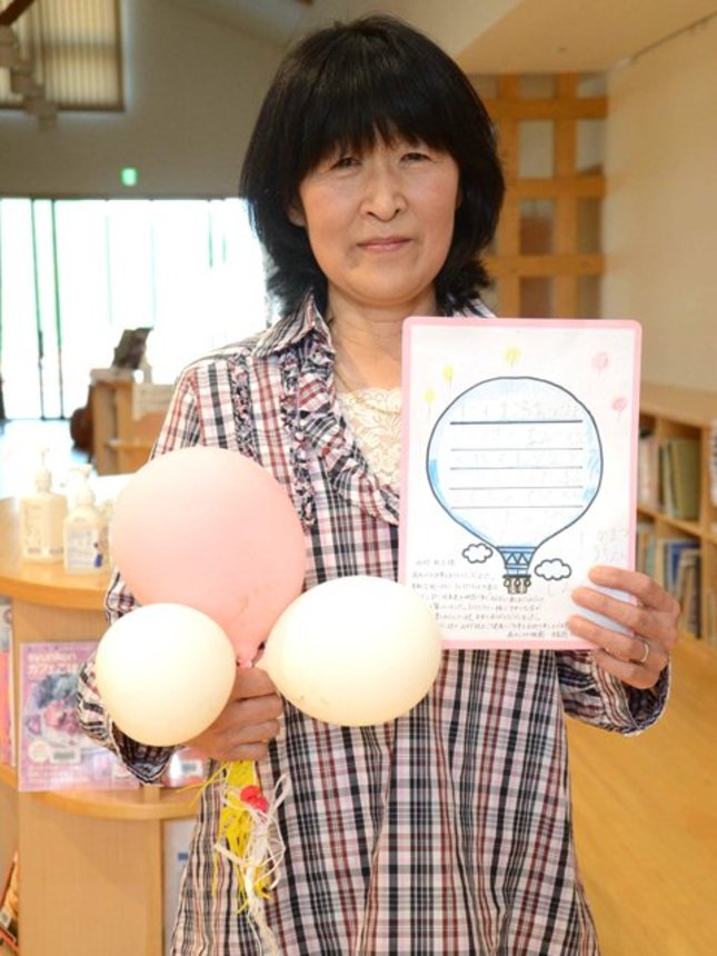 発見した風船と園児から届いたお礼の手紙を手にする西村敦子さん＝中津川市阿木、阿木交流センター