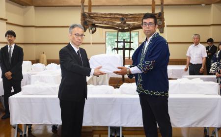 　国交省の担当者からアイヌの遺骨を受け取る、「インカルシペの会」の安ケ平拓也さん（手前右）＝１４日午前、北海道白老町