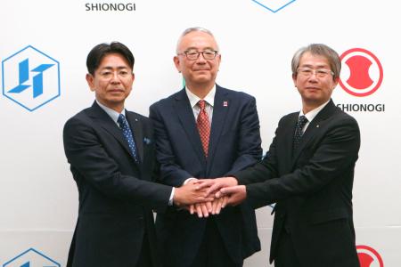 　握手する塩野義製薬の手代木功社長（中央）と日本たばこ産業の嶋吉耕史副社長（左）、鳥居薬品の近藤紳雅社長＝７日午後、東京都千代田区