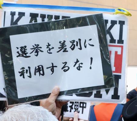 　参院選候補者の街頭演説に対し、抗議のメッセージを掲げる人＝１２日、川崎市