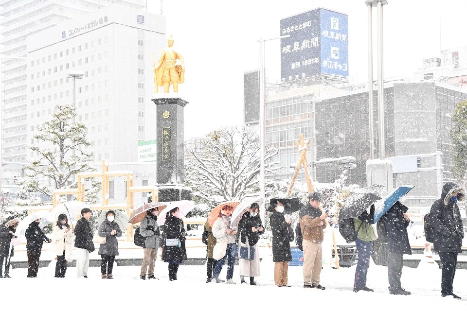 大雪の影響でバスに遅れが生じ、バスを待つ列は黄金の信長像前まで伸びた＝２４日午前７時５０分、岐阜市のJR岐阜駅北口