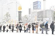 大雪の影響でバスに遅れが生じ、バスを待つ列は黄金の信長像前まで伸びた＝２４日午前７時５０分、岐阜市のJR岐阜駅北口