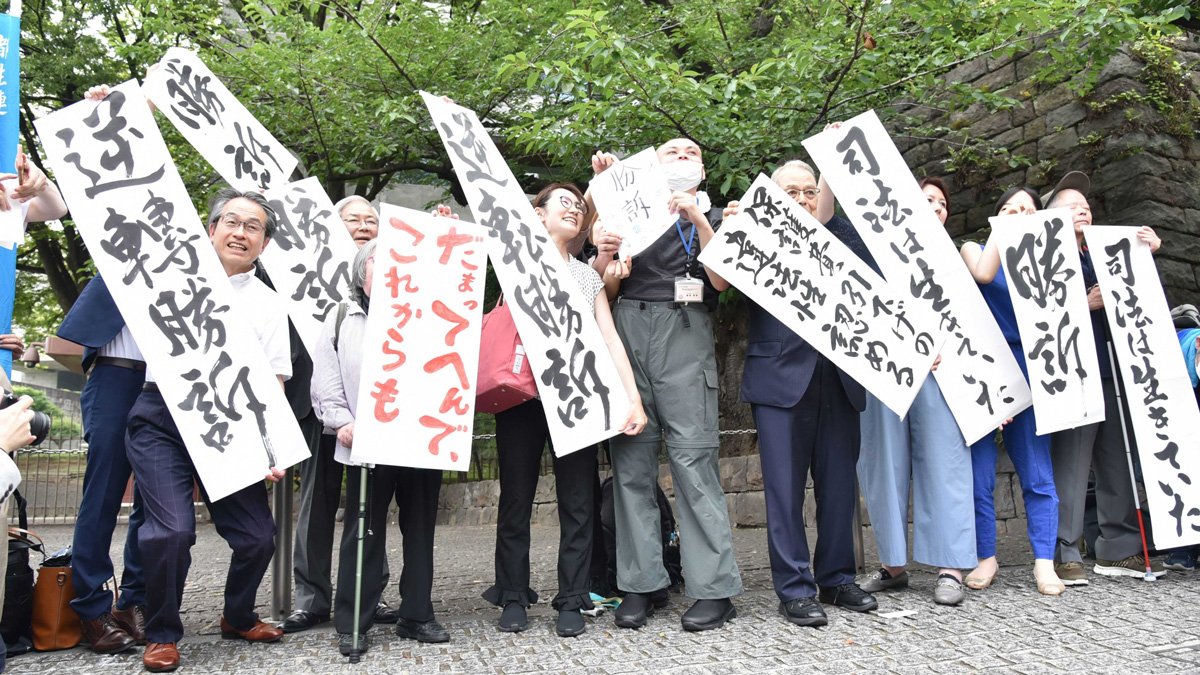 生活保護基準額の引き下げを巡る訴訟の判決を受け、喜ぶ原告や弁護士＝６月、東京都千代田区隼町、最高裁判所前
