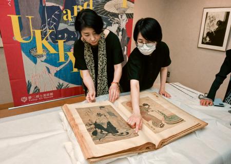 　竹久夢二が収集した浮世絵のスクラップブック。左は「夢二郷土美術館」の小嶋ひろみ館長代理＝２３日、岡山市