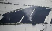 　堤防が決壊し冠水した千葉県・印旛沼の近くの太陽光発電施設から上がる煙＝２４日午前１１時、成田市（共同通信社ヘリから）