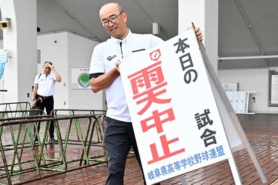 雨天中止の看板を出す県高野連関係者＝１６日午前６時３３分、岐阜市長良福光、長良川球場