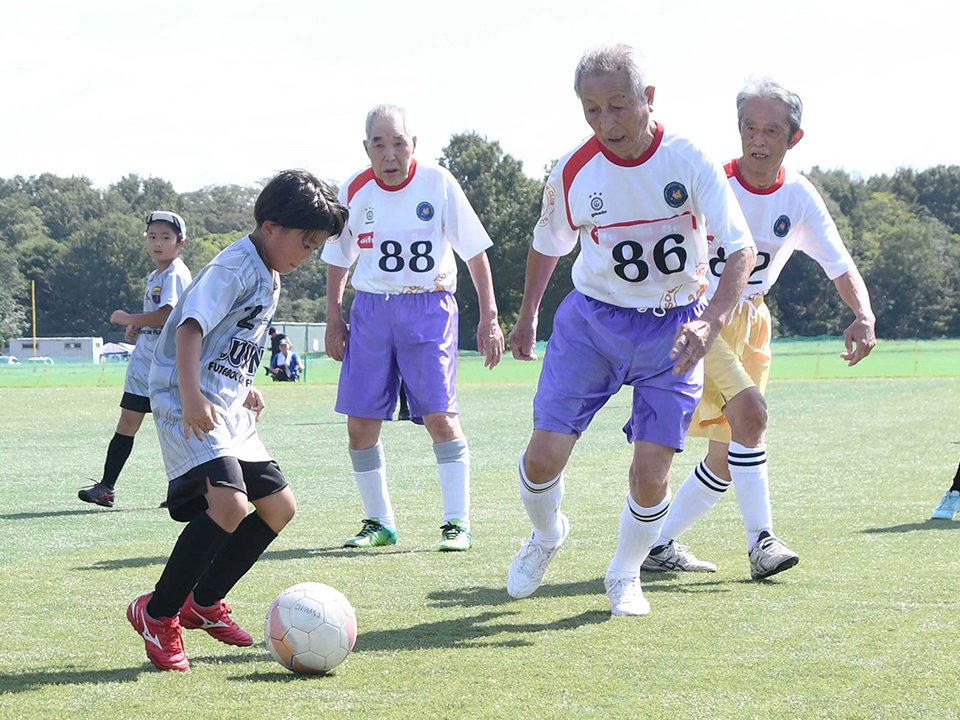 懸命な守備で小学生の攻撃を阻む高齢者＝各務原市下中屋町、市総合運動公園