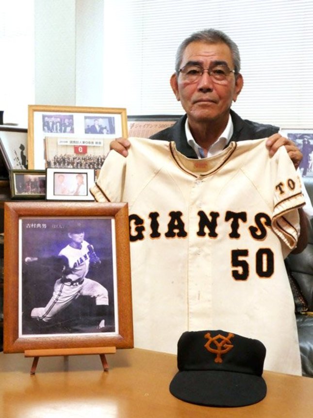 当時のユニホームを掲げる吉村典男さん。巨人一筋のプロ野球人生だった＝恵那市山岡町原、吉村さん宅