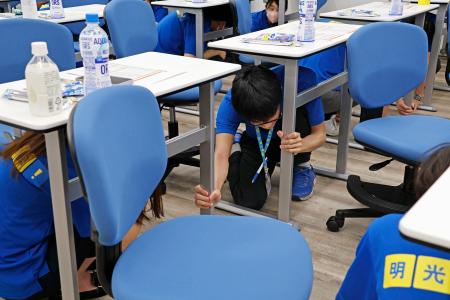 　防災訓練で机の下に隠れる学習塾講師＝２日午前、大阪市鶴見区