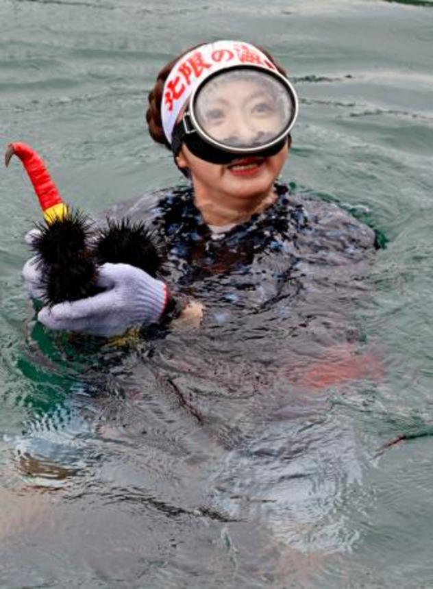 　採れたウニを観光客らにみせる海女＝１日午前、岩手県久慈市