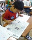 新聞の紙面の中から、習った文字を探す１年生＝同 