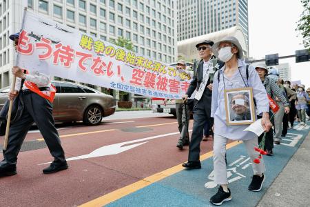 　戦争被害の救済を求めてデモ行進する人たち＝１９日午後、東京都内