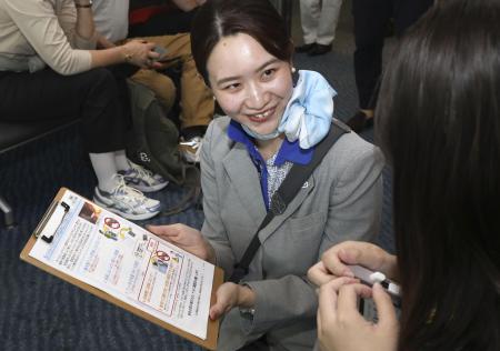 　モバイルバッテリーの持ち込みに関して、乗客に協力を求める全日空グループの地上職員＝２０２５年７月、羽田空港