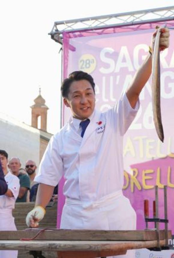 　イタリア・コマッキオで開かれたウナギ祭りで、さばいたウナギを見せる田舎庵の緒方仁さん＝３日（共同）