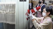 蒸気を当てて成型する機械に編み上げた靴下をセットしていく従業員