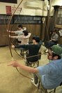 約７メートル先の的に向けて弓を構えると、一瞬だけ店内は静かになる。遊戯とはいえみんな真剣な表情で的に向かう＝高山市朝日町、半弓道場