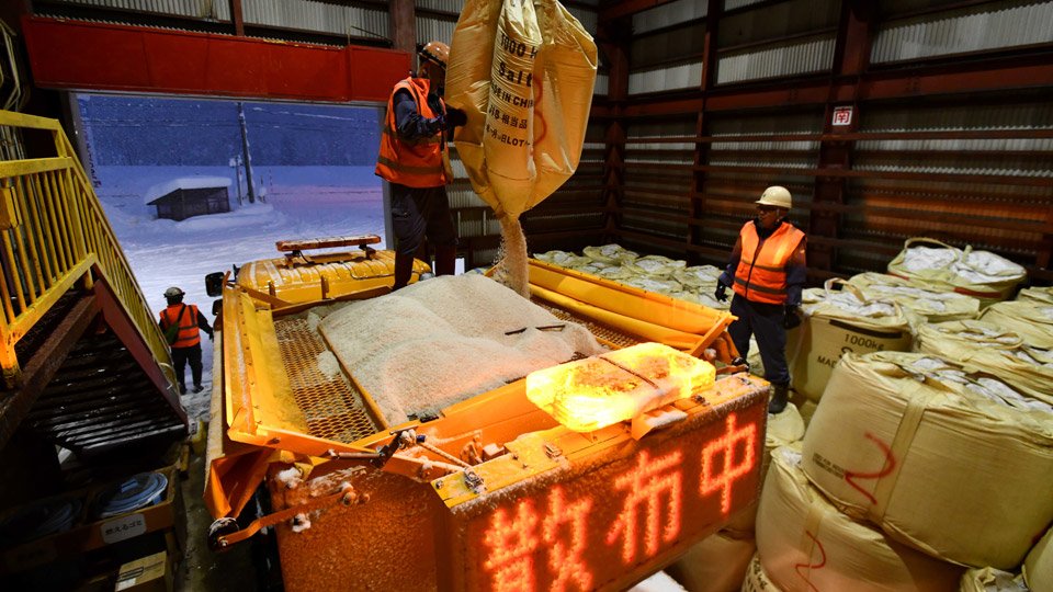凍結防止剤を散布車に補充する作業員。１袋は１トンある＝飛騨市古川町数河、数河除雪センター