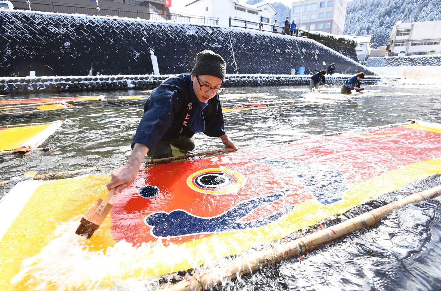 冷たい川の水でのりを落とすこいのぼりの寒ざらし作業＝１８日午前１０時６分、岐阜県郡上市八幡町、小駄良川