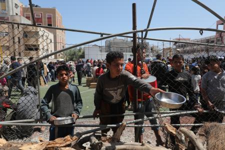 　１８日、パレスチナ自治区ガザの難民キャンプで食事の配給を受け取る子どもたち（アナトリア通信提供・ゲッティ＝共同）