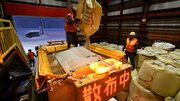 凍結防止剤を散布車に補充する作業員。１袋は１トンある＝飛騨市古川町数河、数河除雪センター