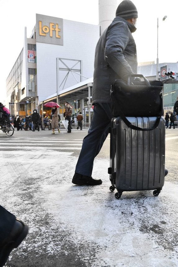 雪が舞う中を歩く人たち＝２５日午前８時７分、岐阜市神田町