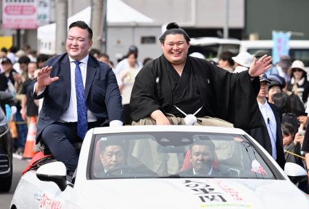 　石川県津幡町で行われた大相撲の横綱昇進を祝うパレードで、沿道に集まった人たちの声援に応える大の里関。左は二所ノ関親方＝２９日午後