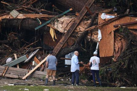 　洪水後の川の土手で残骸を見る人々＝５日、米南部テキサス州（ＡＰ＝共同）