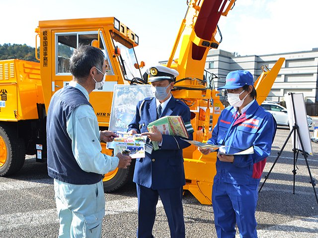 道の駅利用客に、車両の早めの冬装備を呼び掛ける関係者＝美濃市曽代、道の駅美濃にわか茶屋