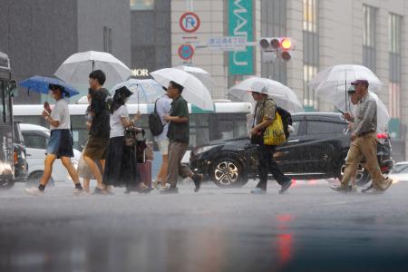 　強い雨が降る中、傘を差して歩く人たち＝１０日午後、福岡市