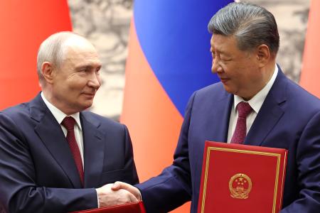 　調印式で握手するロシアのプーチン大統領（左）と中国の習近平国家主席＝２０日、北京の人民大会堂（共同）