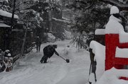 雪かきに追われる住民＝２５日午前７時４０分、高山市神明町