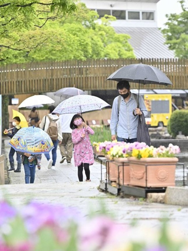 傘を差して水辺の通りを歩く親子連れ＝２９日午前１１時５６分、各務原市川島笠田町、河川環境楽園オアシスパーク