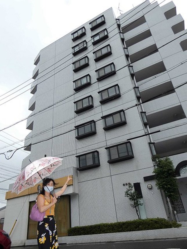 蜂の巣ができたマンションの最上階を指さす大家の安藤庸子さん＝岐阜市竜田町