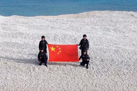　南シナ海の南沙諸島にある鉄線礁に上陸し、中国国旗を掲げる海警局員（中国国営中央テレビの「微信（ウィーチャット）」公式アカウントから、共同）