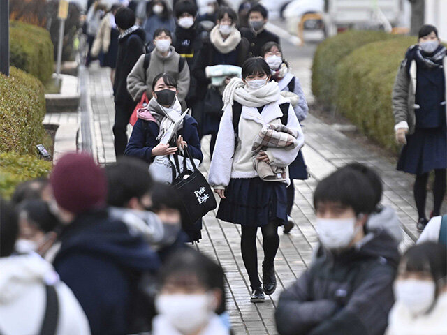 大学入学共通テストの初日、防寒具を手にマスク姿で試験会場に向かう受験生たち＝１６日午前７時５３分、岐阜市柳戸、岐阜大