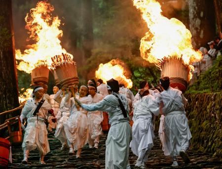 　熊野那智大社で開かれた例大祭「那智の扇祭り」。白装束の氏子らが燃えさかる大たいまつを担ぎ練り歩いた＝１４日午後、和歌山県那智勝浦町