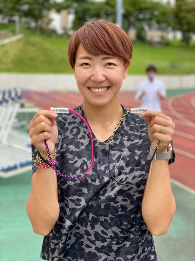 手首に巻くアクセフのスポーツブレスレットを手にする陸上の寺田明日香選手（サンフォード提供）