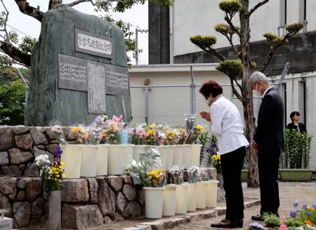 　紫雲丸の沈没事故から７０年となり、犠牲となった生徒の名前が刻まれた高知市立南海中の石碑に手を合わせる参列者＝１１日午前、高知市